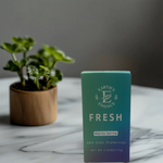 Teal box labeled 'Earth's Essence Fresh' on a marble surface with a plant in the background