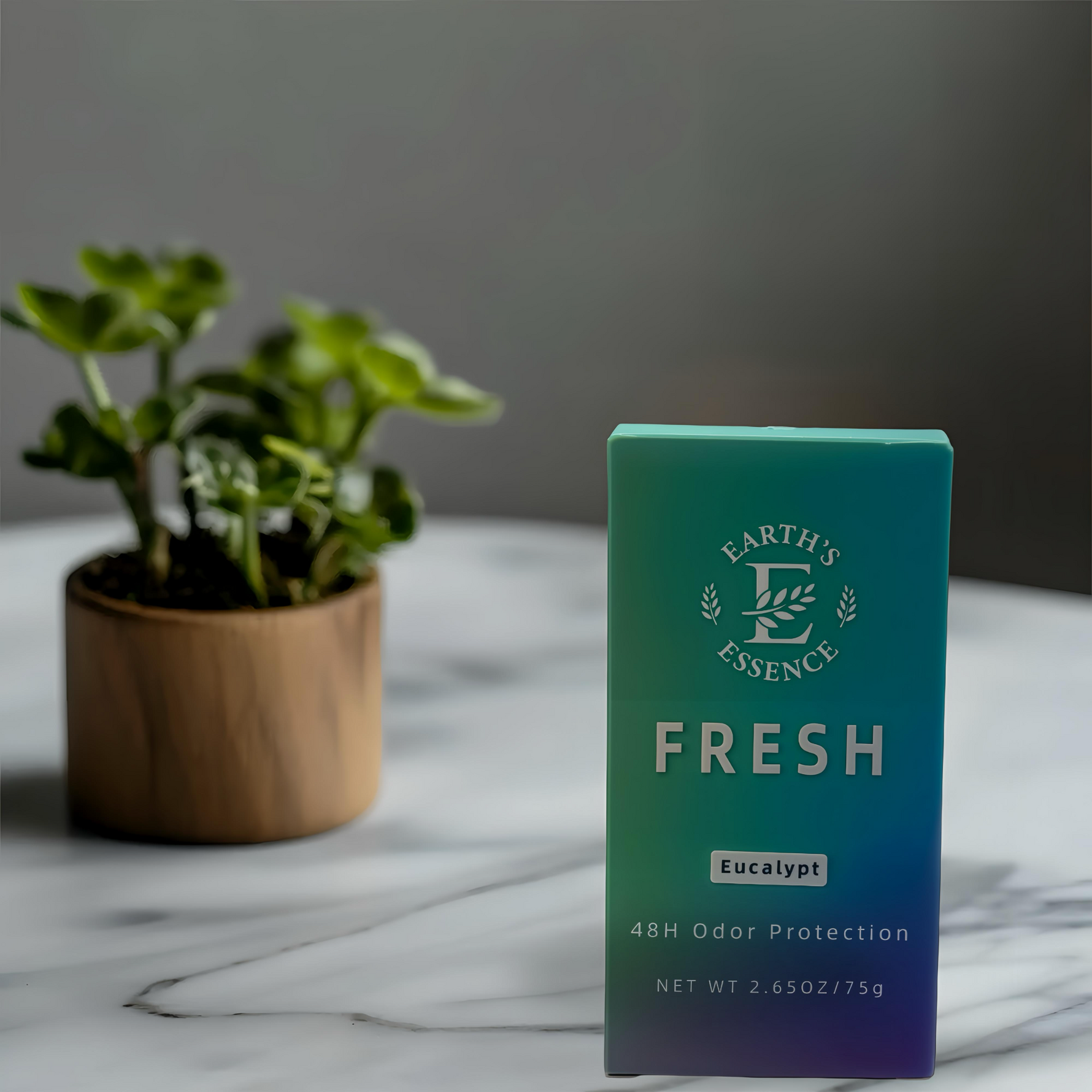 Green box labeled 'Earth's Essence Fresh' on a marble surface with a plant in the background